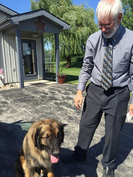 A man standing next to a dog in front of a building