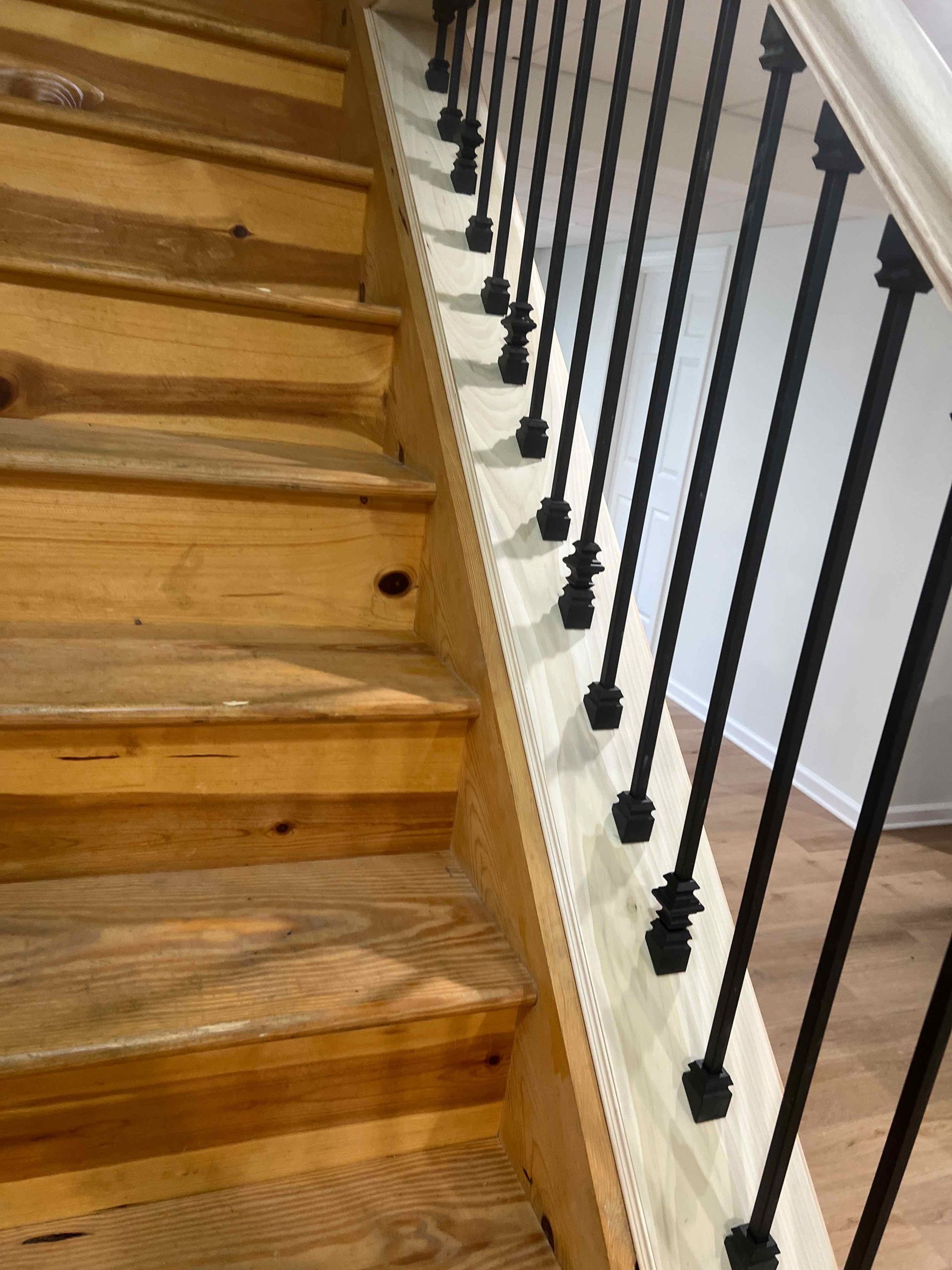 A wooden staircase with a black railing in a house.