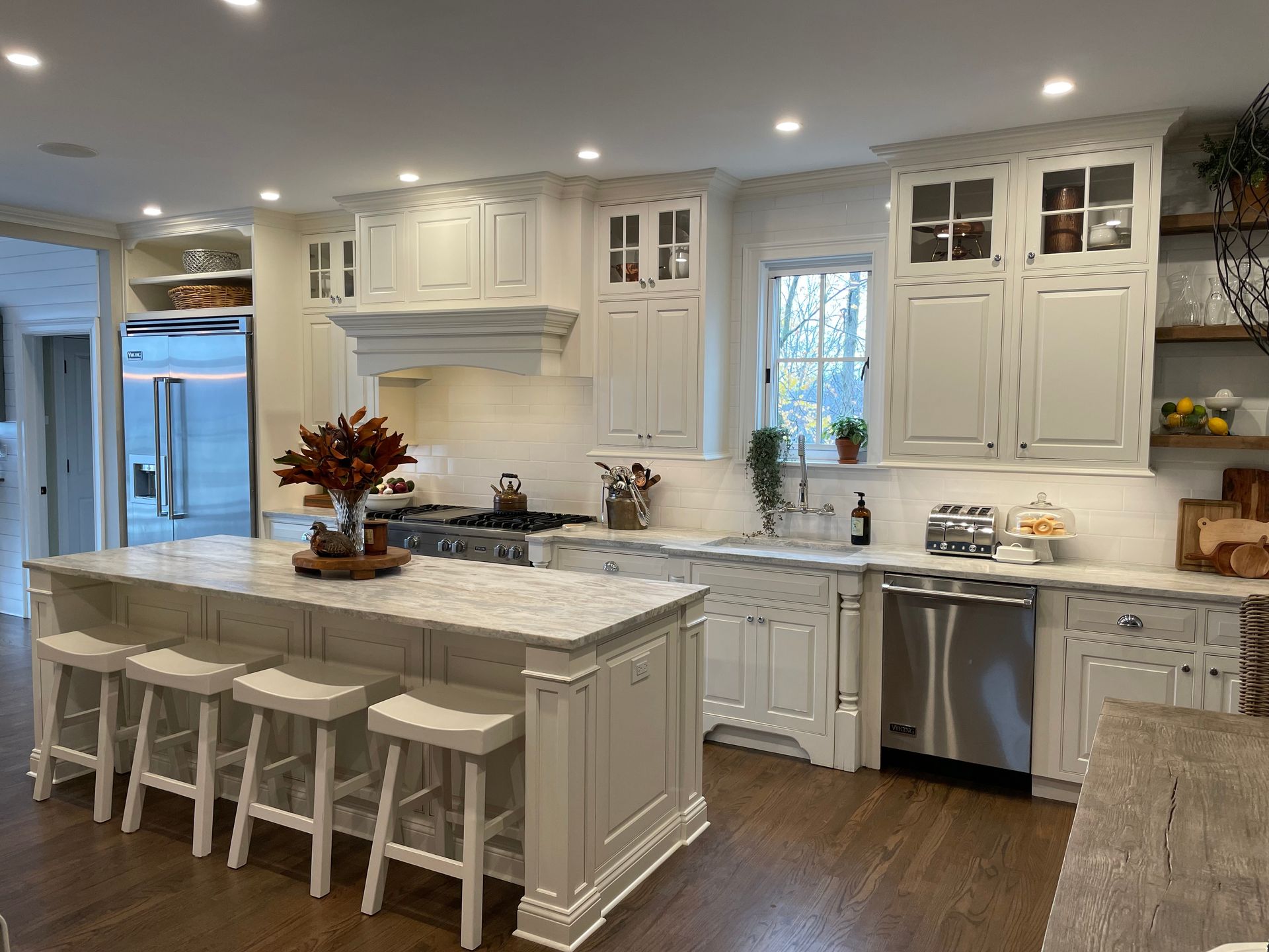 A kitchen with white cabinets and stools and a large island.