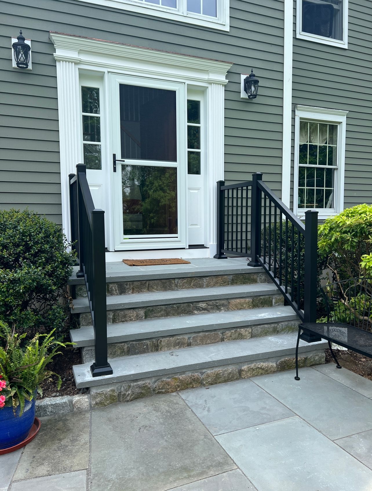 A house with stairs leading up to the front door and a black railing.