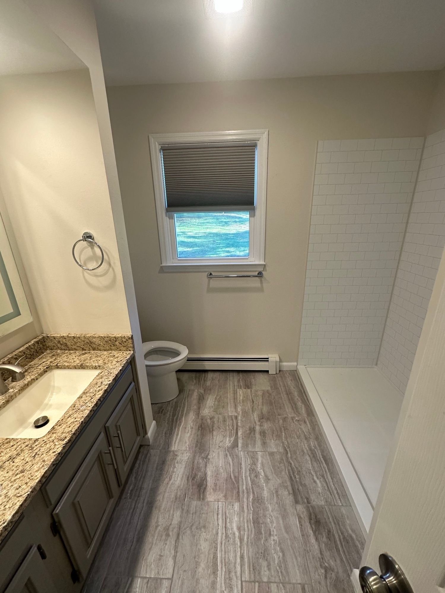 A bathroom with a sink , toilet , shower and window.