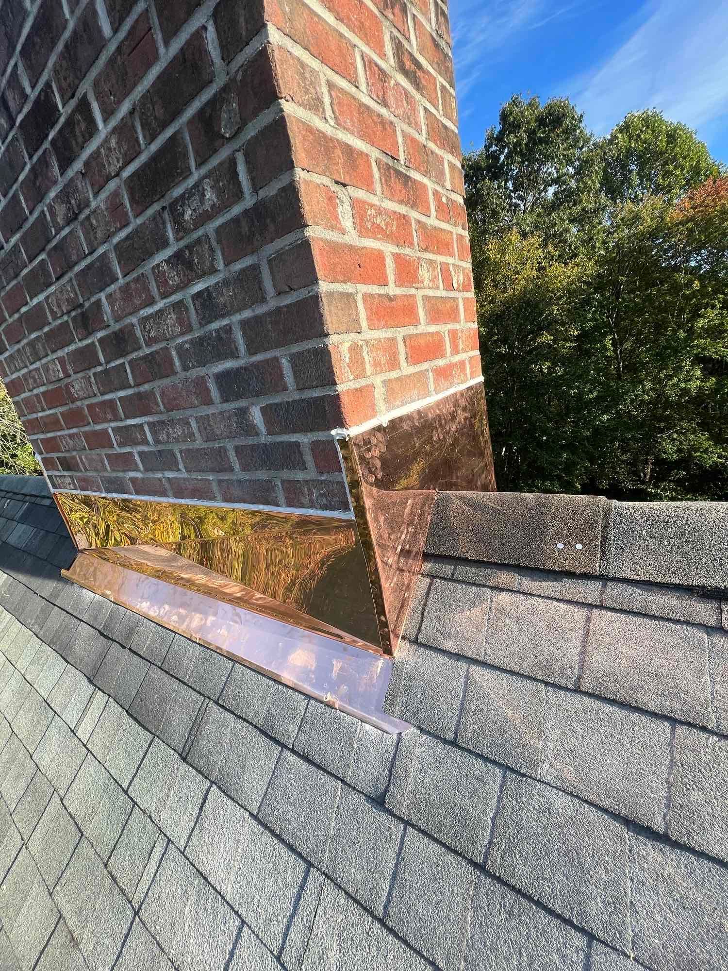 A brick chimney is sitting on top of a roof.