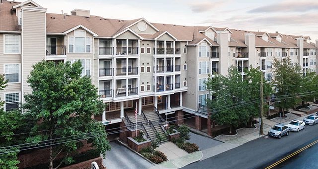 An aerial view of a large apartment building with cars parked in front of it.