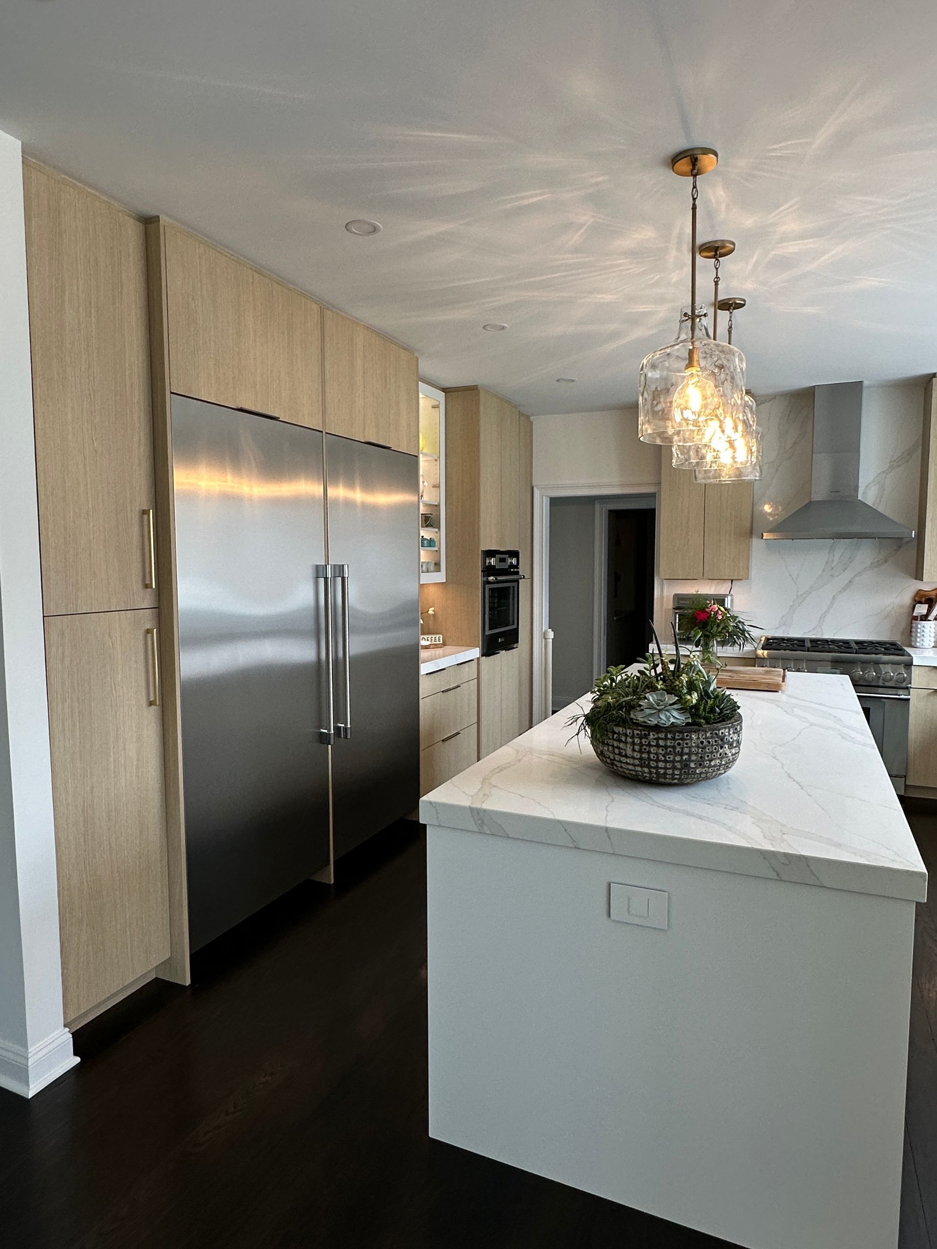 There is a bar in the middle of the room with a refrigerator.