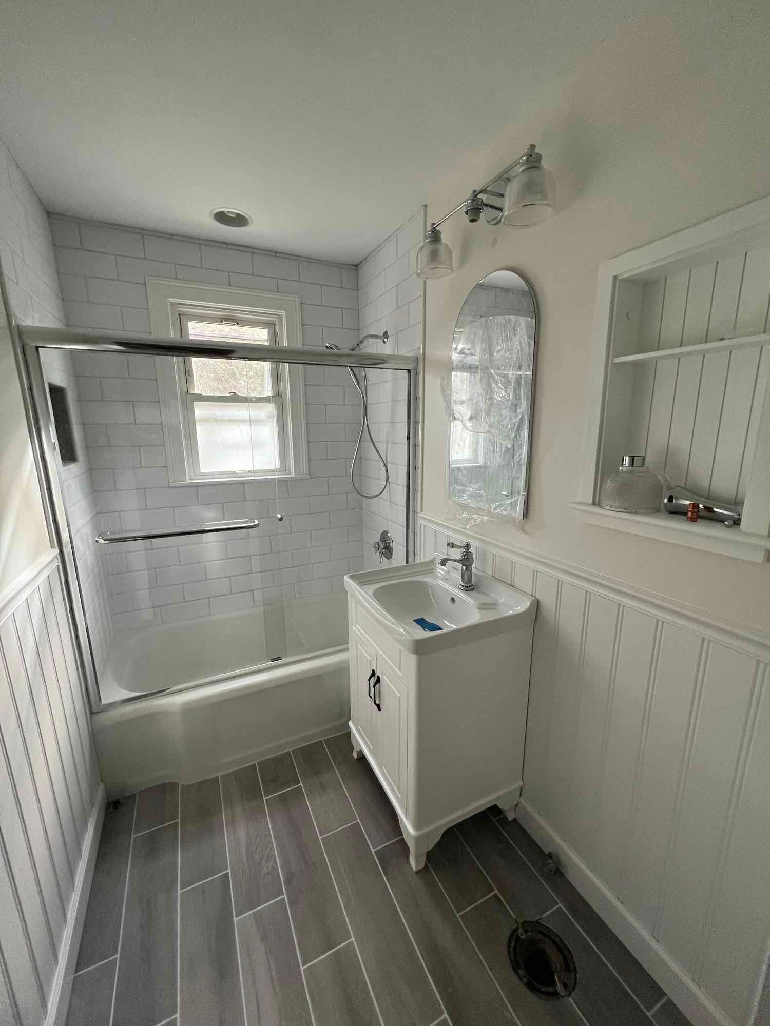 A bathroom with a sink , tub , shower and mirror.