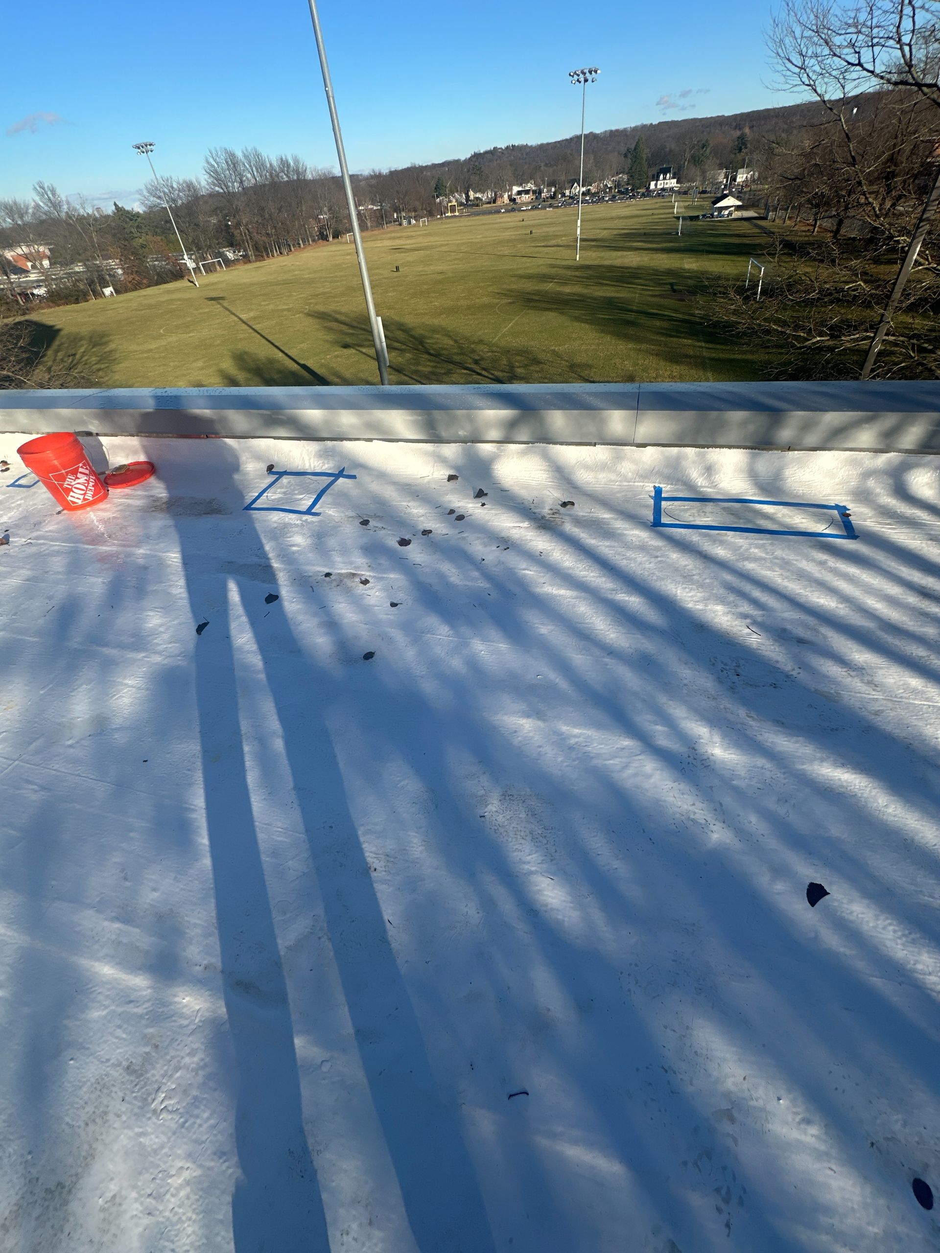 A snowy roof with a view of a field in the background.