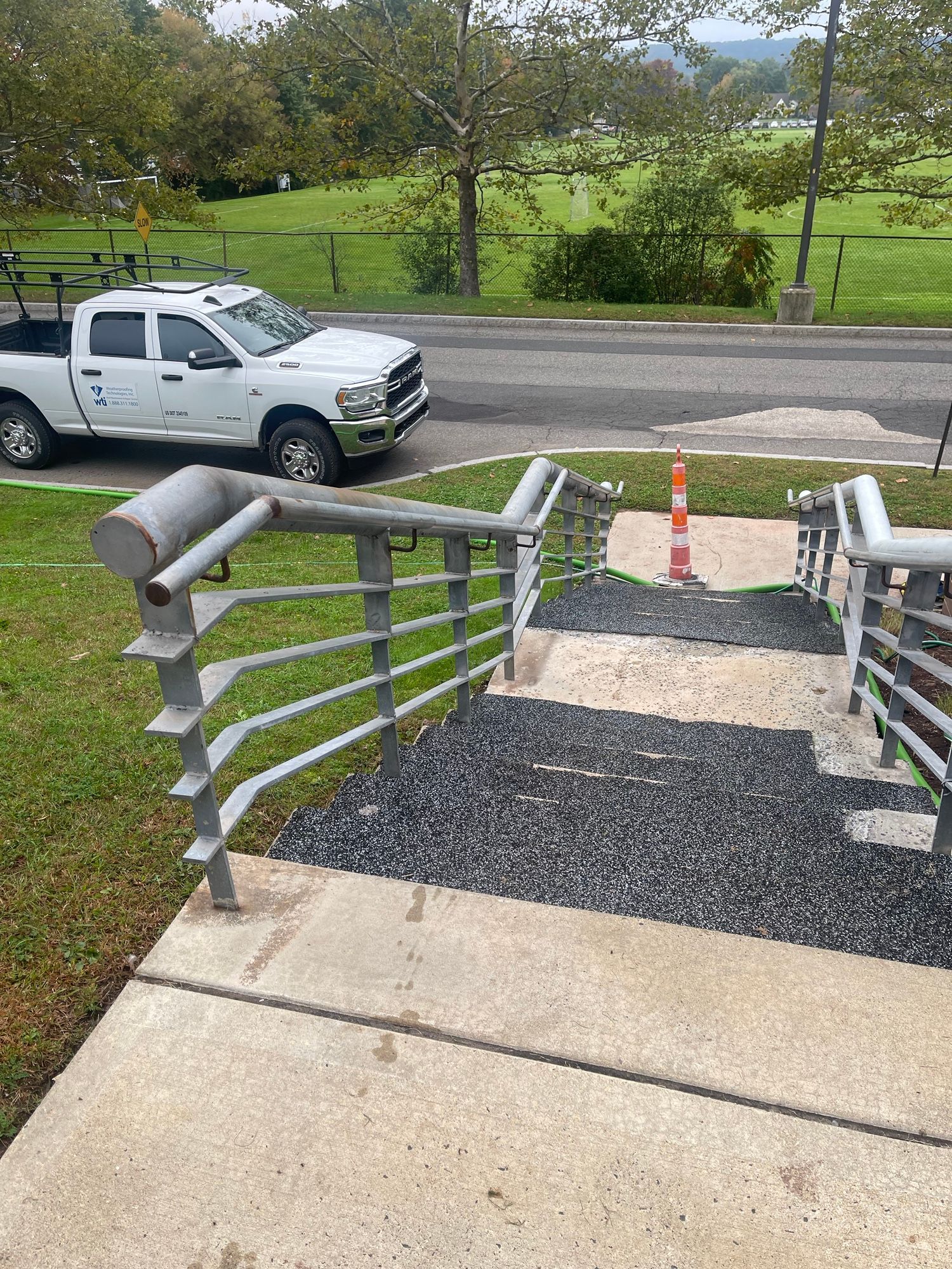 A white truck is parked on the side of the road next to a set of stairs.