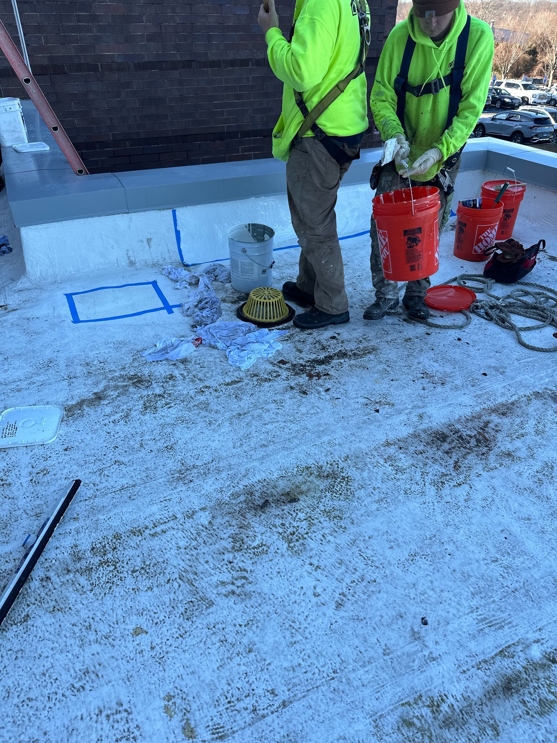 Two men are standing on top of a snow-covered roof.