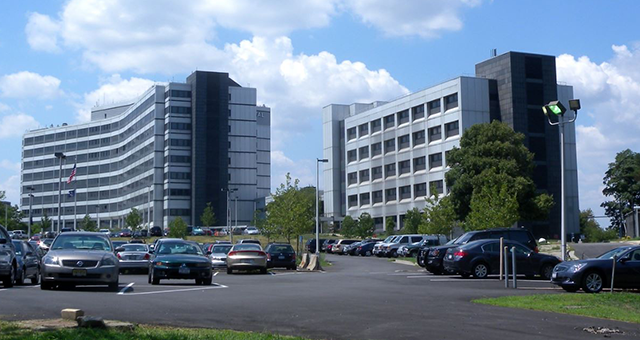 A lot of cars are parked in front of a large building
