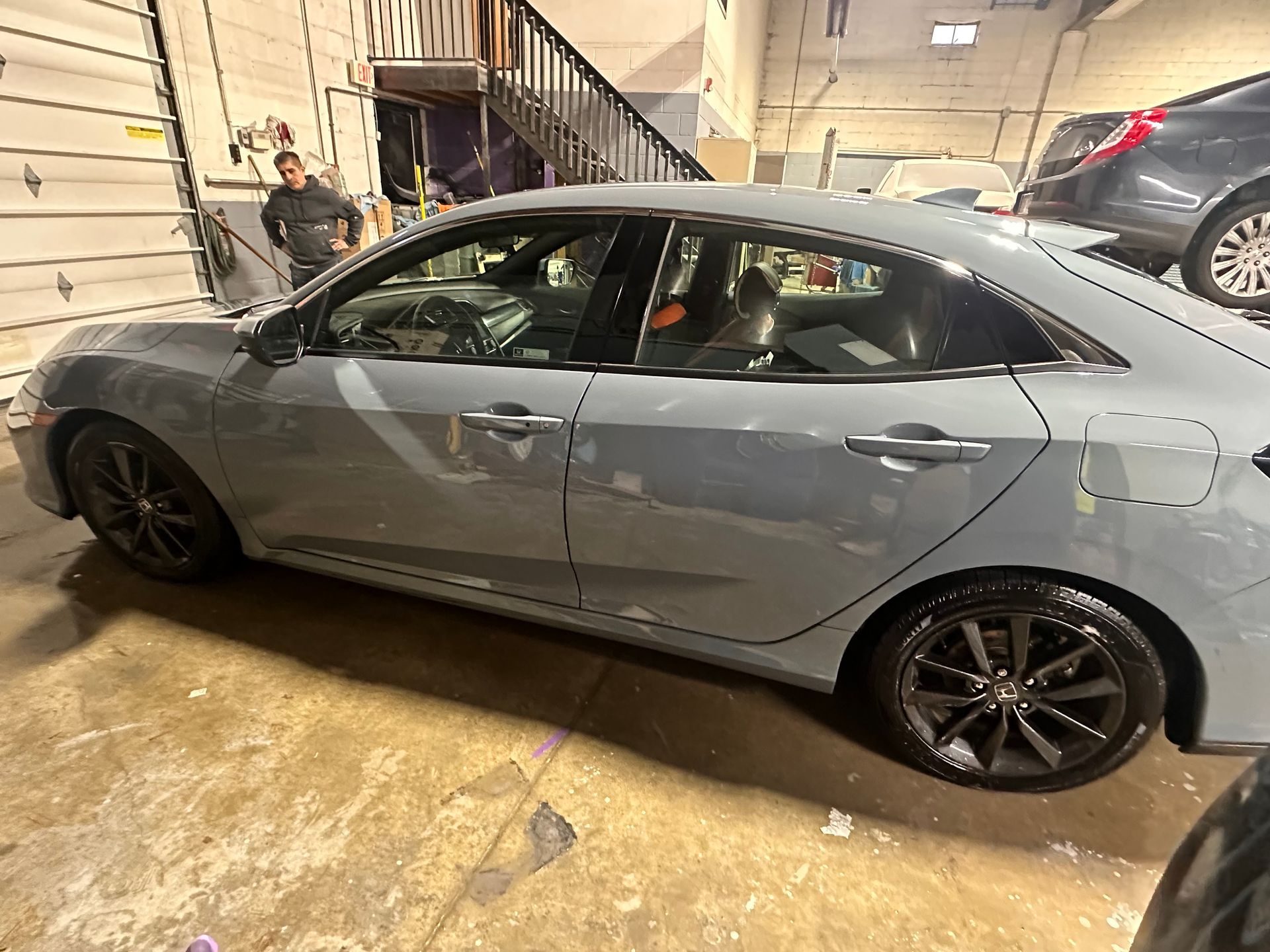 A gray honda civic is parked in a garage.