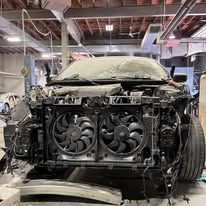 A damaged car is sitting in a garage with its radiator removed.