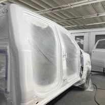 A white van is being painted in a garage.