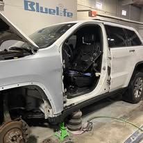 A white jeep is being worked on in a garage.