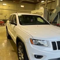 A white jeep grand cherokee is parked in a garage.