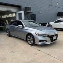 A silver honda accord is parked in front of a garage.