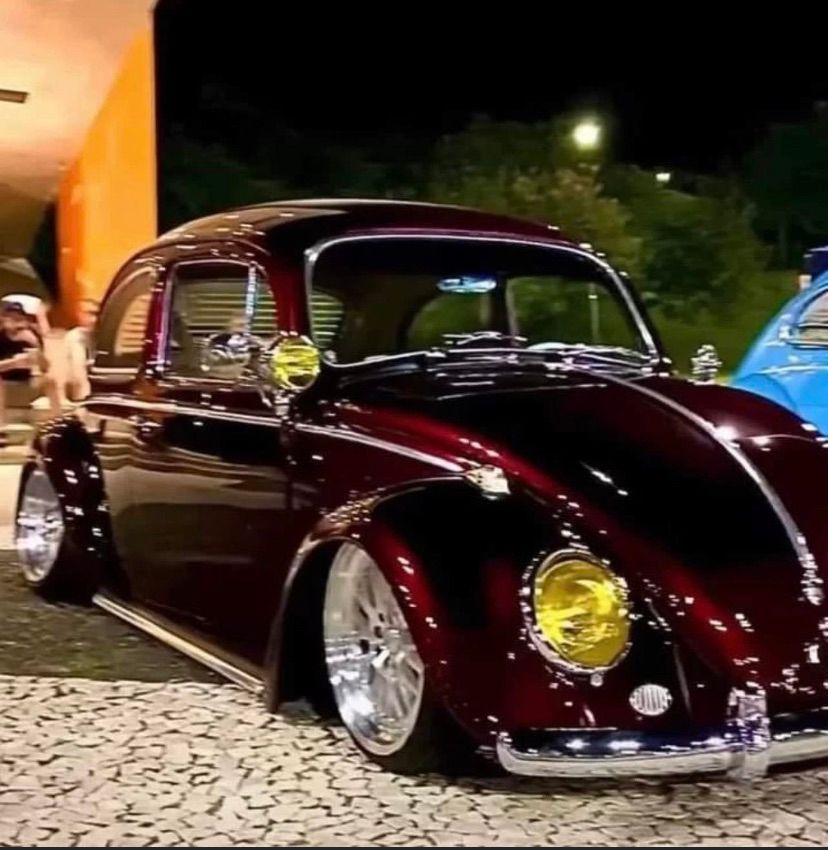 A red car with yellow headlights is parked on a cobblestone street.