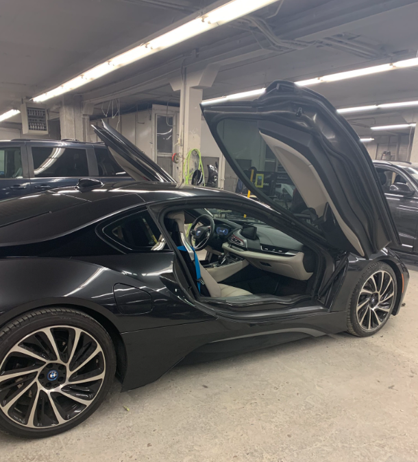 A black sports car is parked in a garage with the door open.