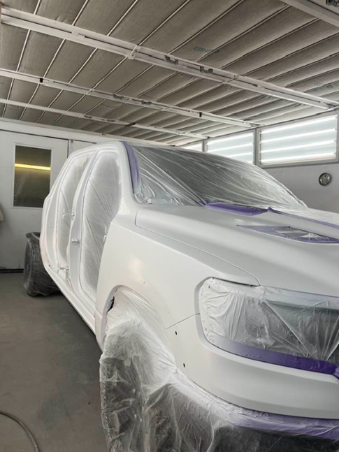 A white truck is being painted in a garage.