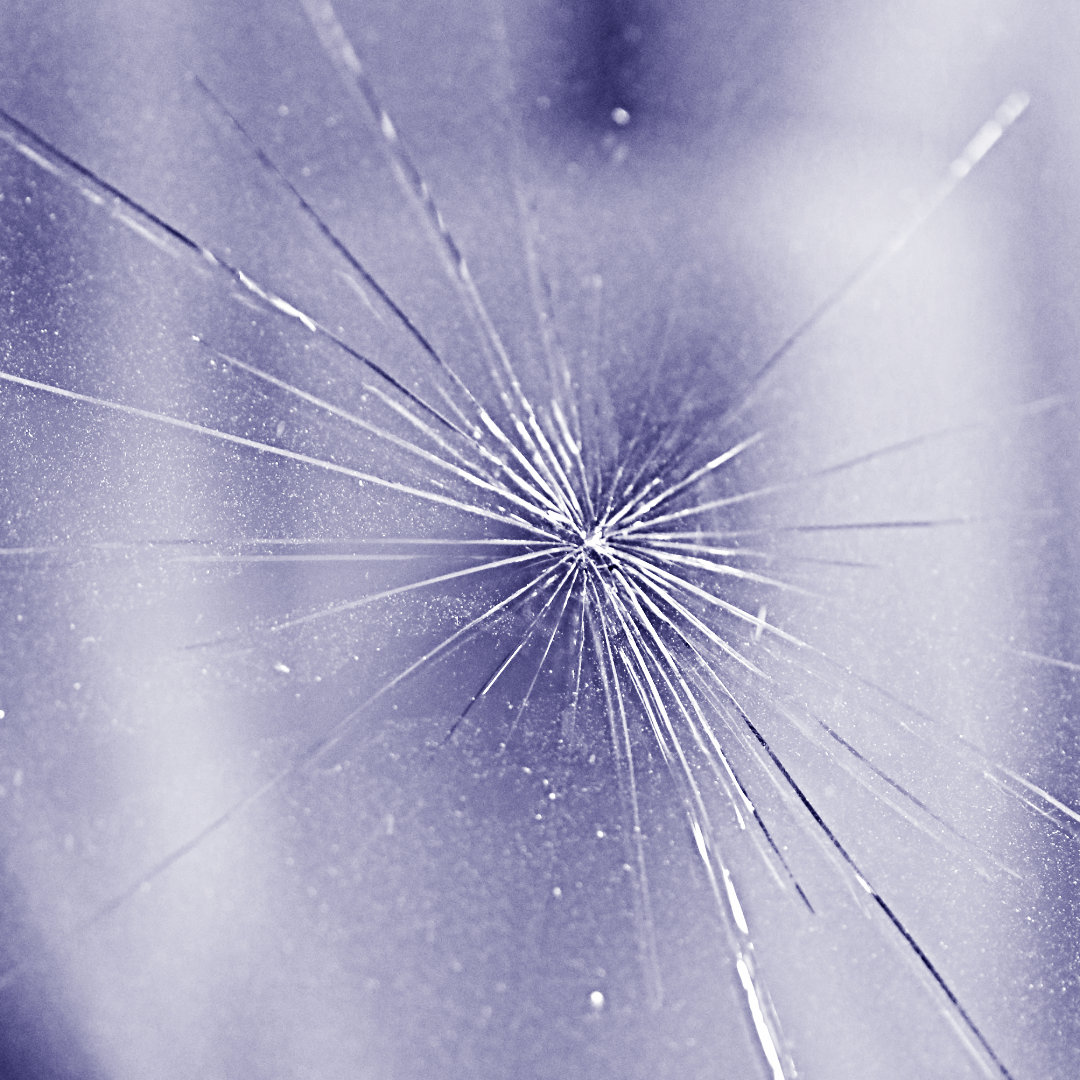 Broken glass with cracks radiating outwards from a central point, light purple hue.