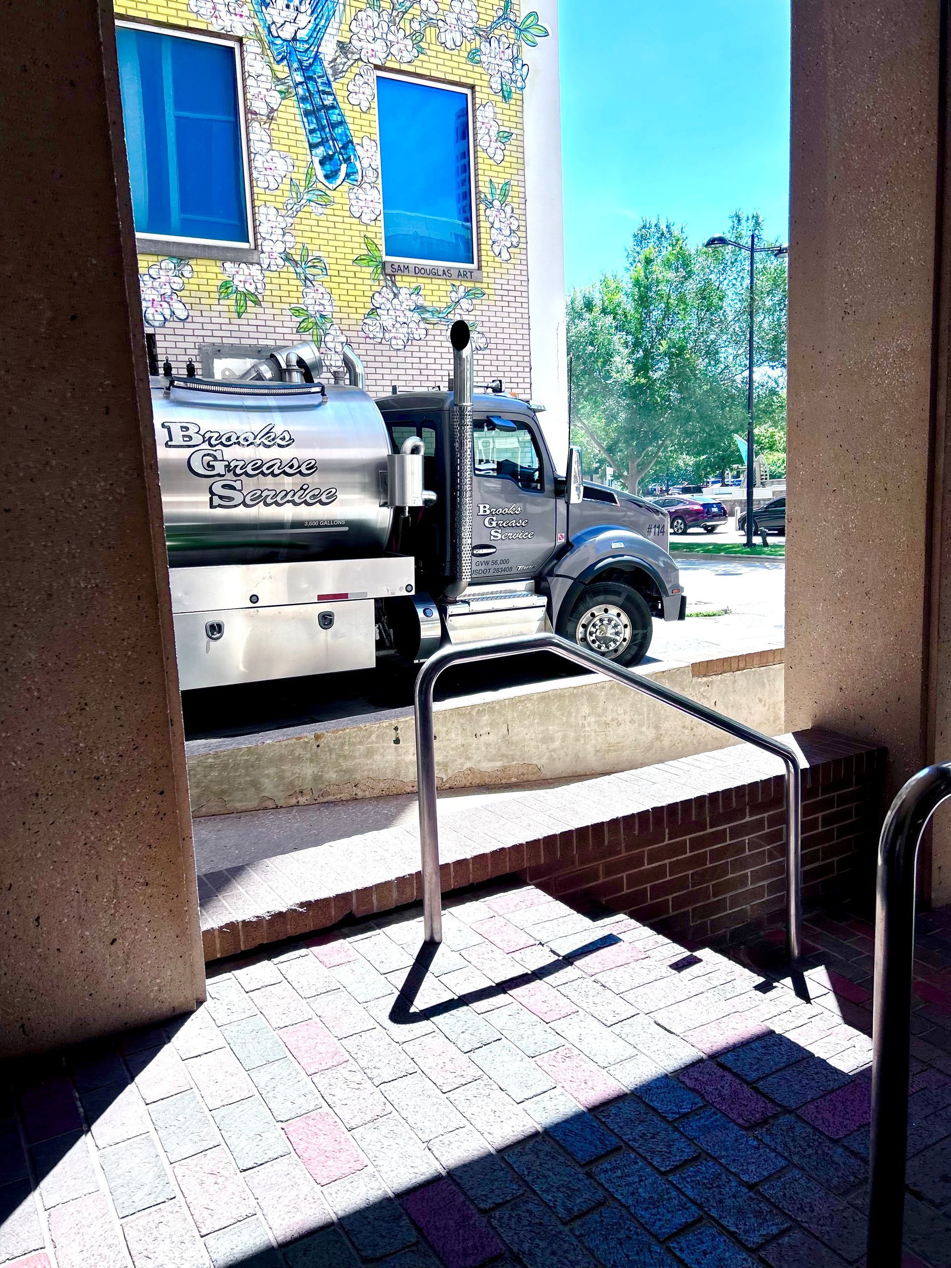 Truck parked near steps and building with mural and blue windows.