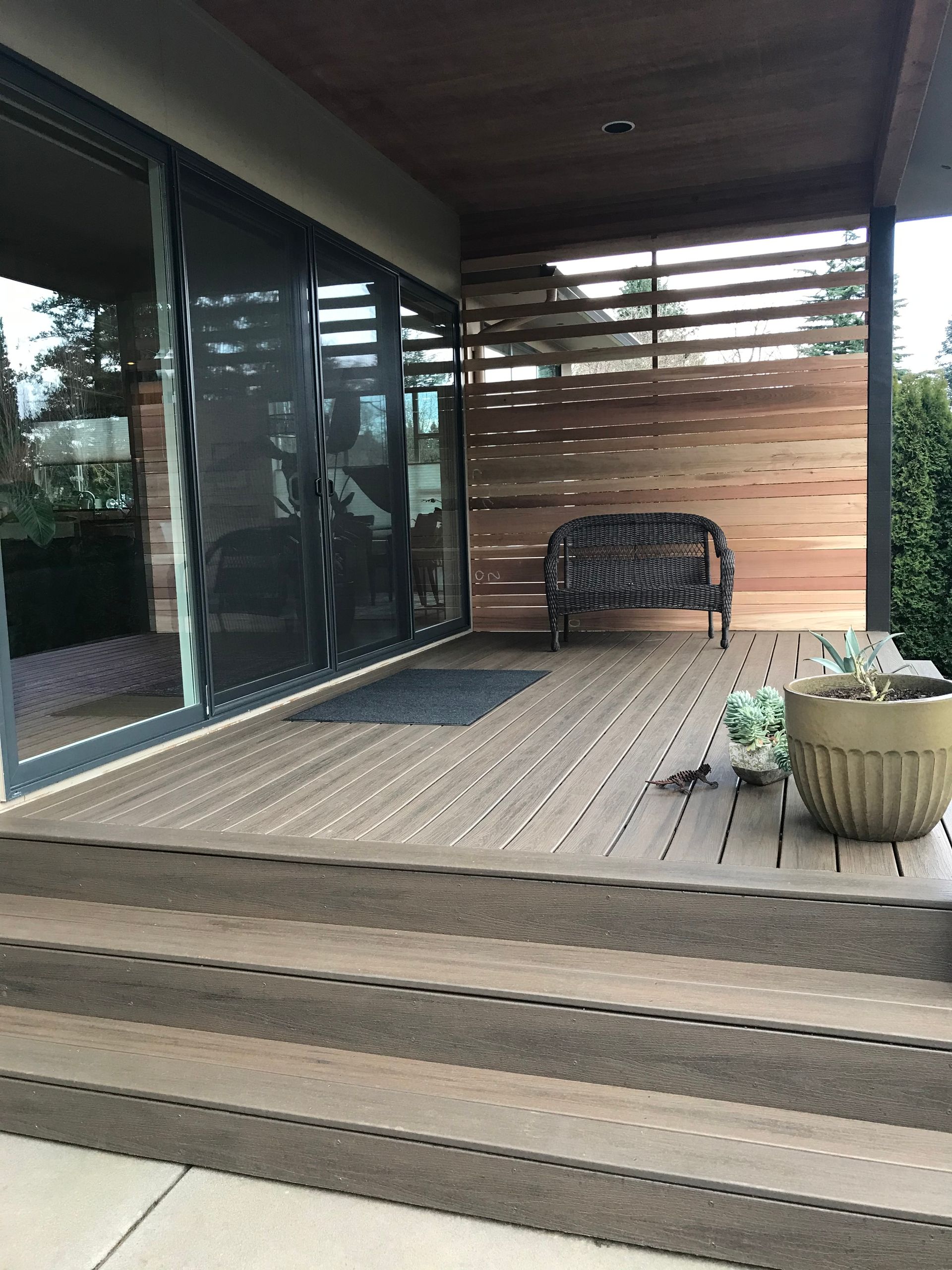 A wooden deck with a couch and potted plants on it