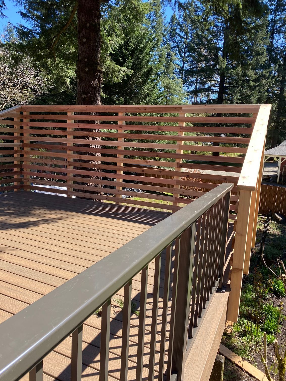 A wooden deck with a metal railing and trees in the background