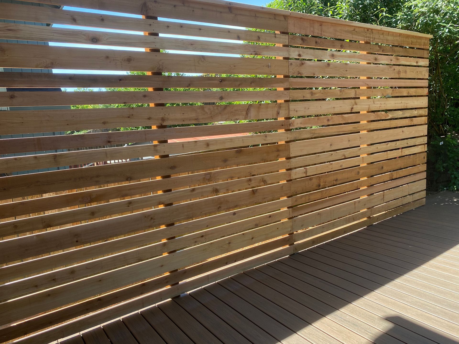 A wooden fence surrounds a deck with trees in the background