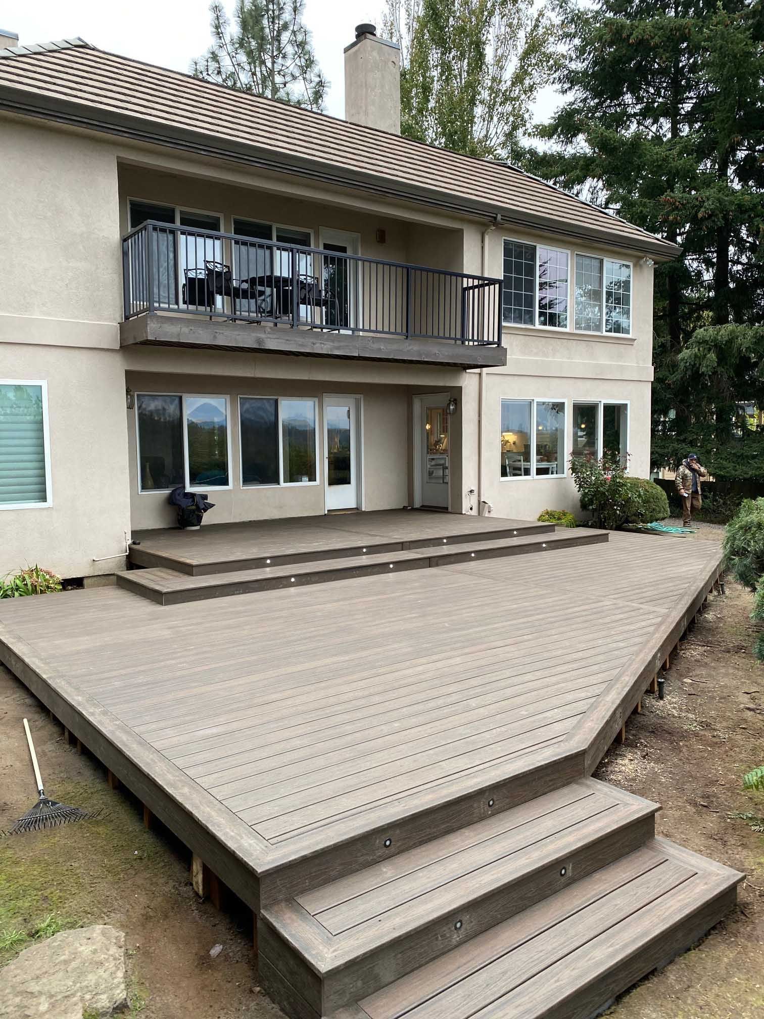 A large house with a large deck and stairs in front of it.