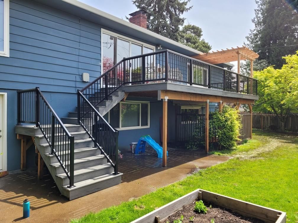 A blue house with a deck and stairs in the backyard.