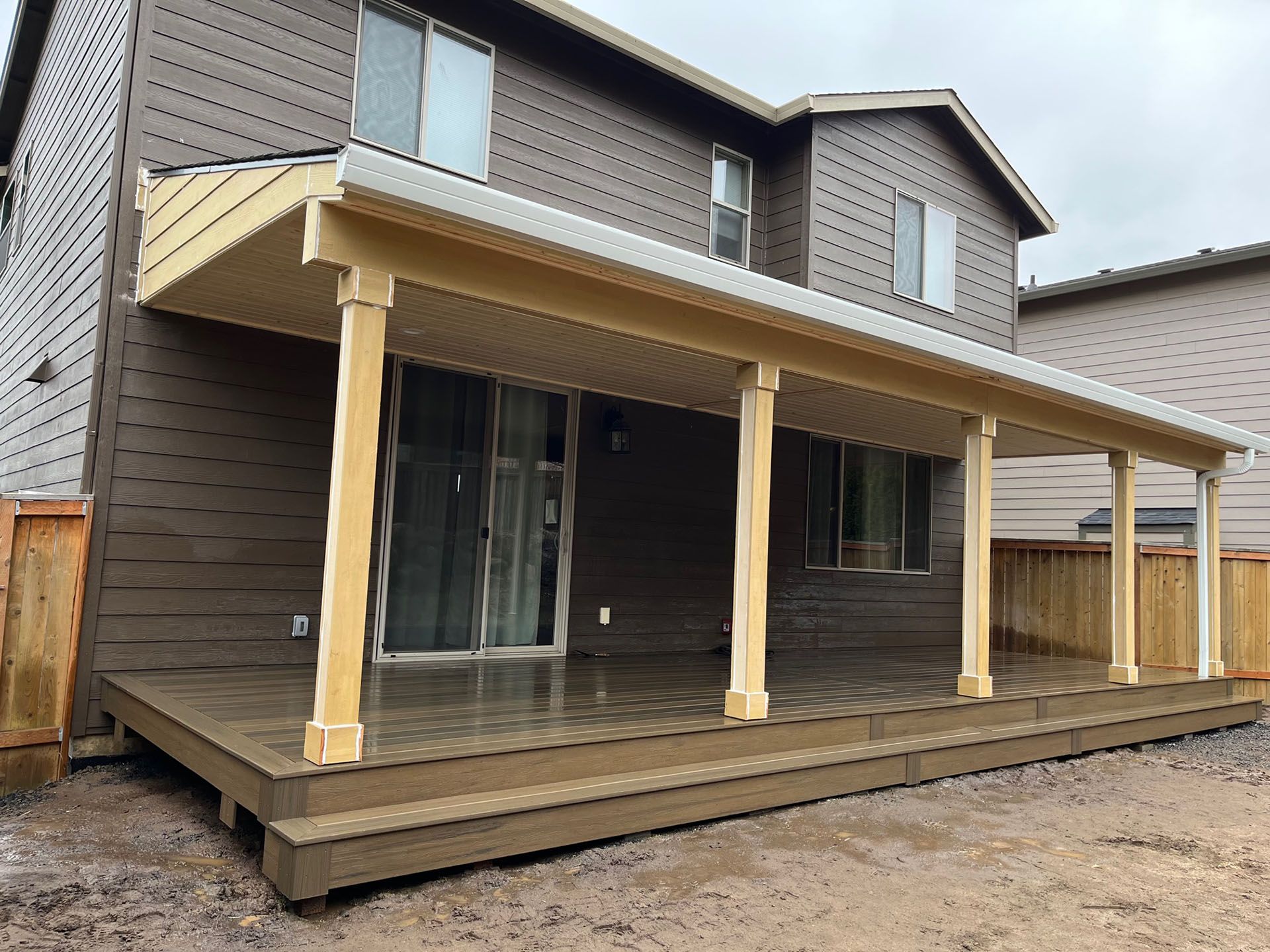 The back of a house with a wooden deck and a covered porch.