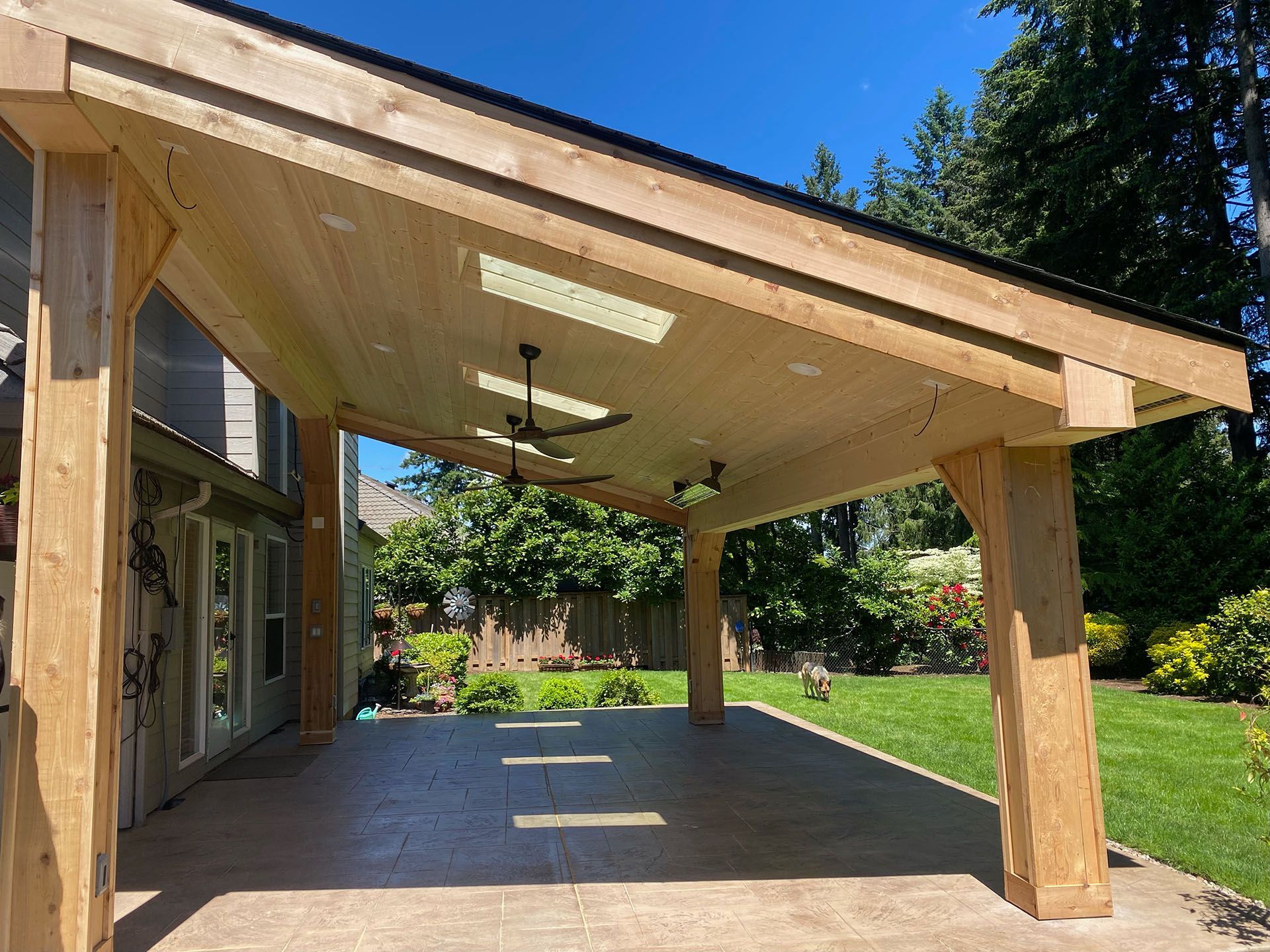 A large wooden pavilion with a ceiling fan in the backyard.