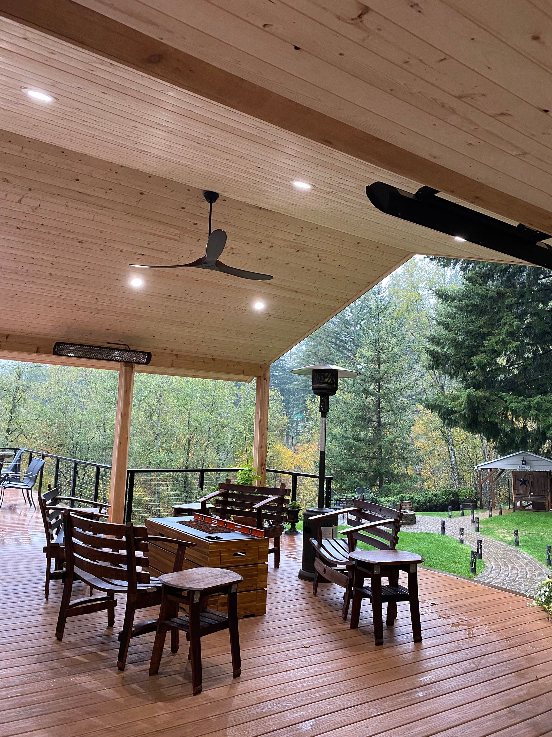 A wooden deck with tables and chairs under a ceiling fan.