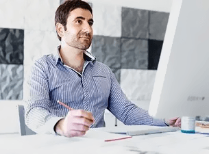 Man holding a pen in front of computer