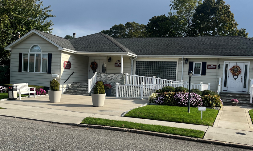A white house with a black roof and a white fence