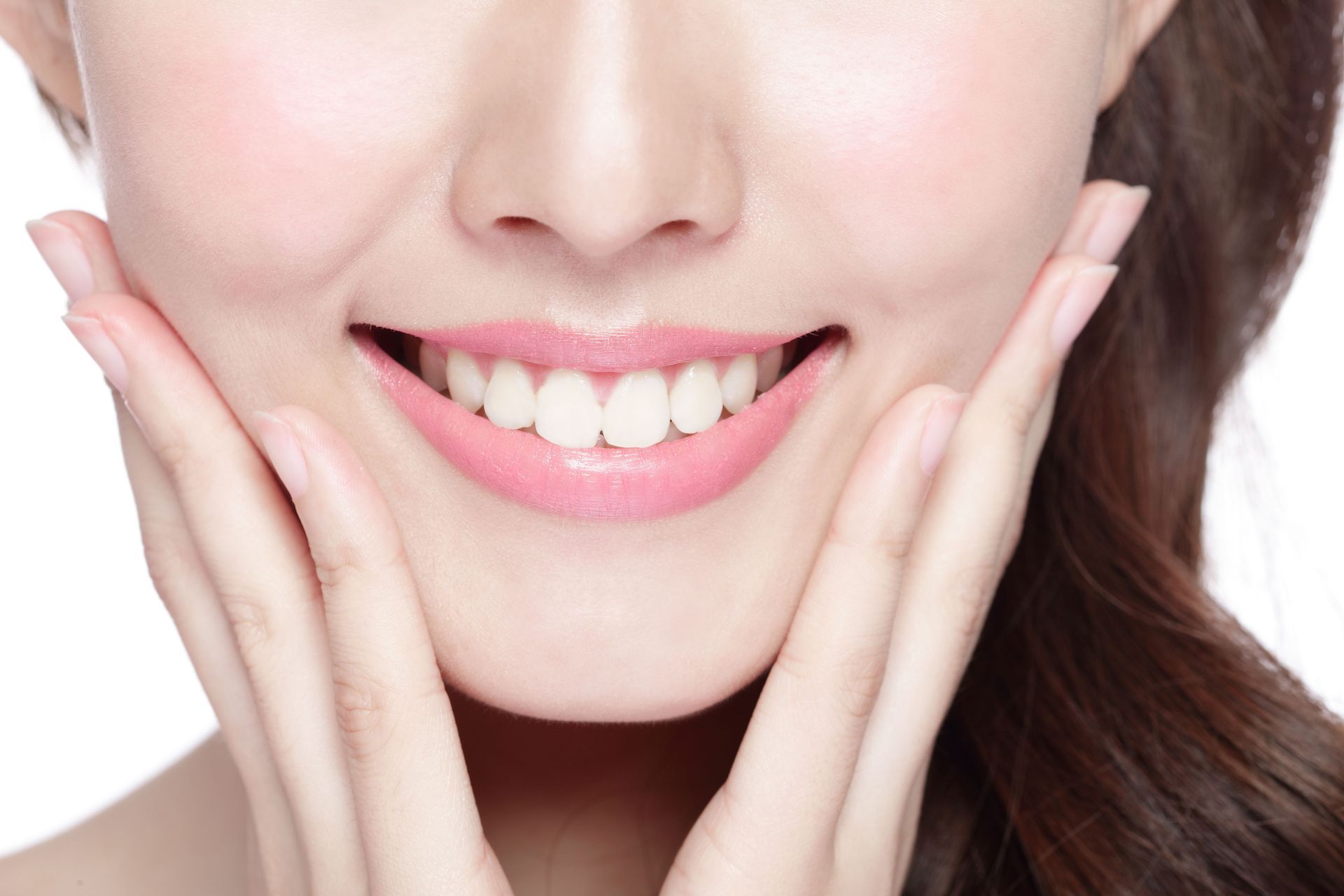 A woman is smiling and touching her face with her hands.