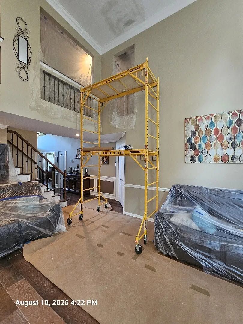 Living room with yellow scaffold, plastic-covered furniture, and staircase in the background