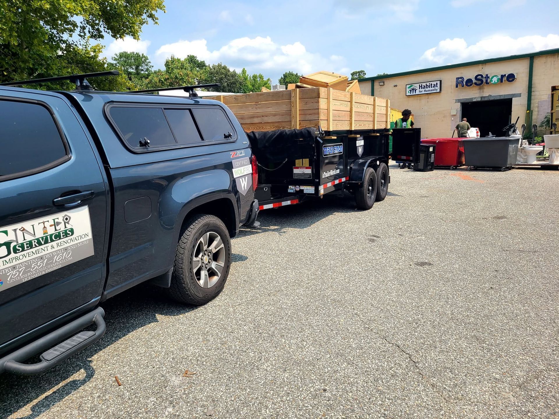 Pickup truck towing a flatbed trailer outside a building with a ReStore sign
