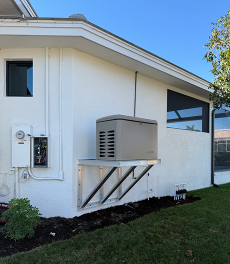 Exterior of white house with gray generator unit mounted on metal brackets beside an electrical panel