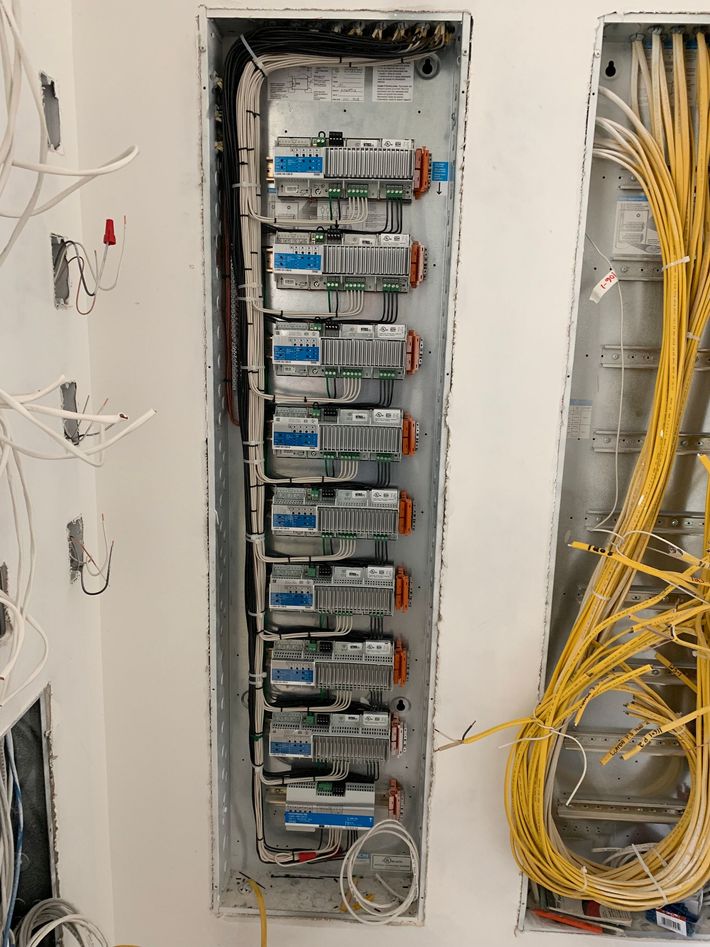 Electrical panel with rows of breakers and bundled yellow cables in a wall recess