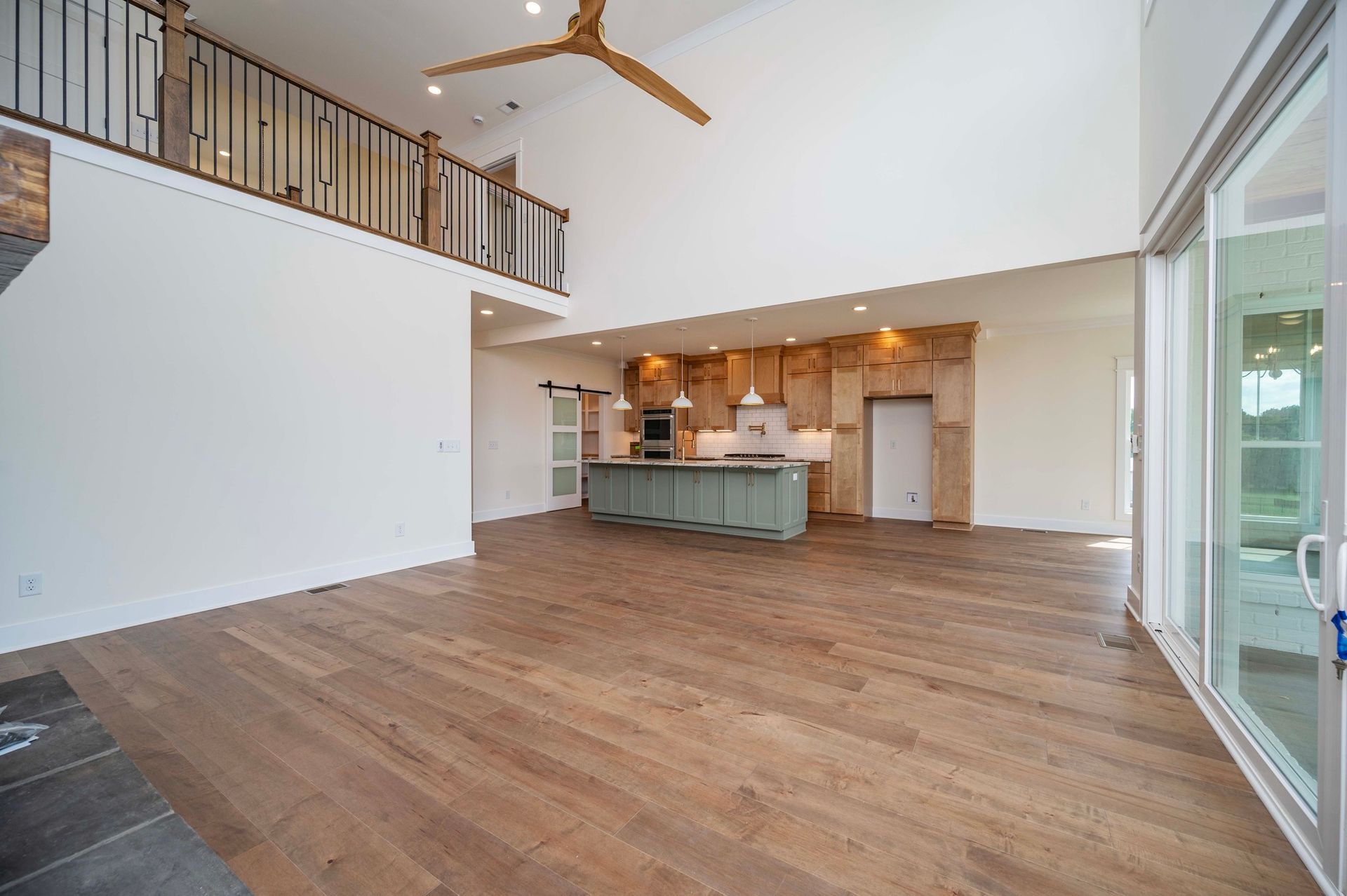Spacious open-concept living area with wood floors, kitchen island, and a loft overlooking the space.