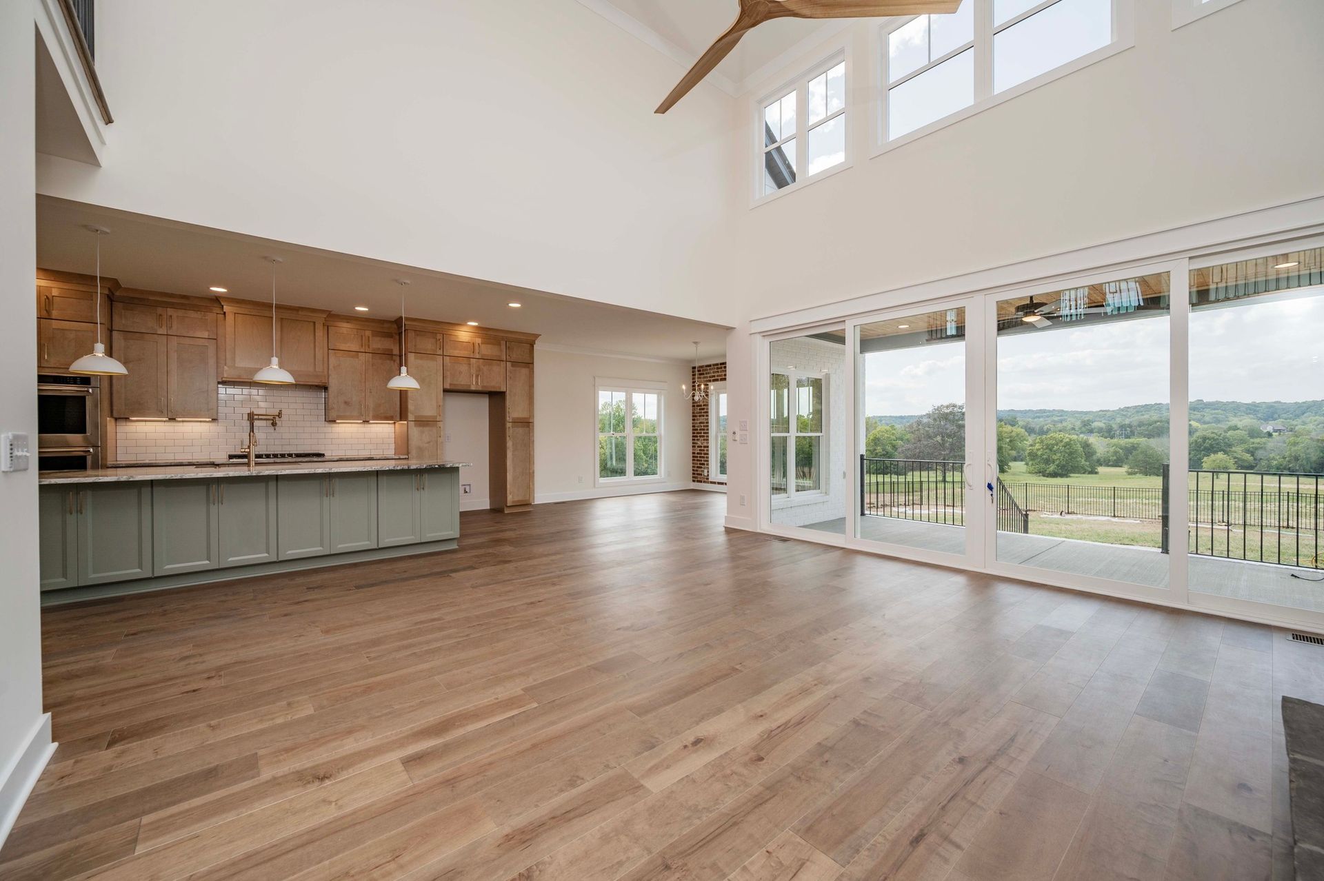 Spacious open-concept living area with kitchen, large windows, and wooden floors.