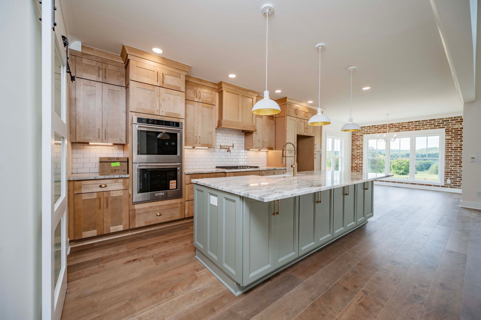 Spacious kitchen with light wood cabinets, green island, and granite countertops. Bright room with large windows.