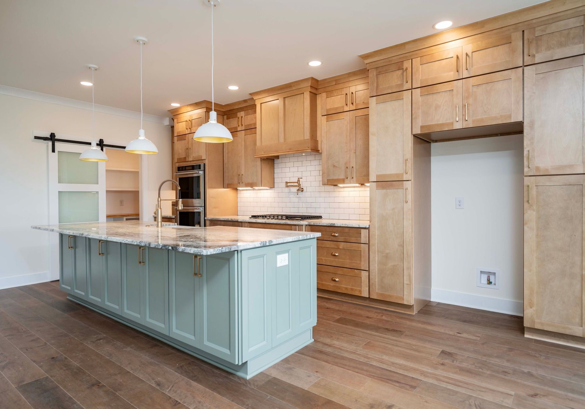 Kitchen with light wood cabinets, blue island, and hardwood floors.