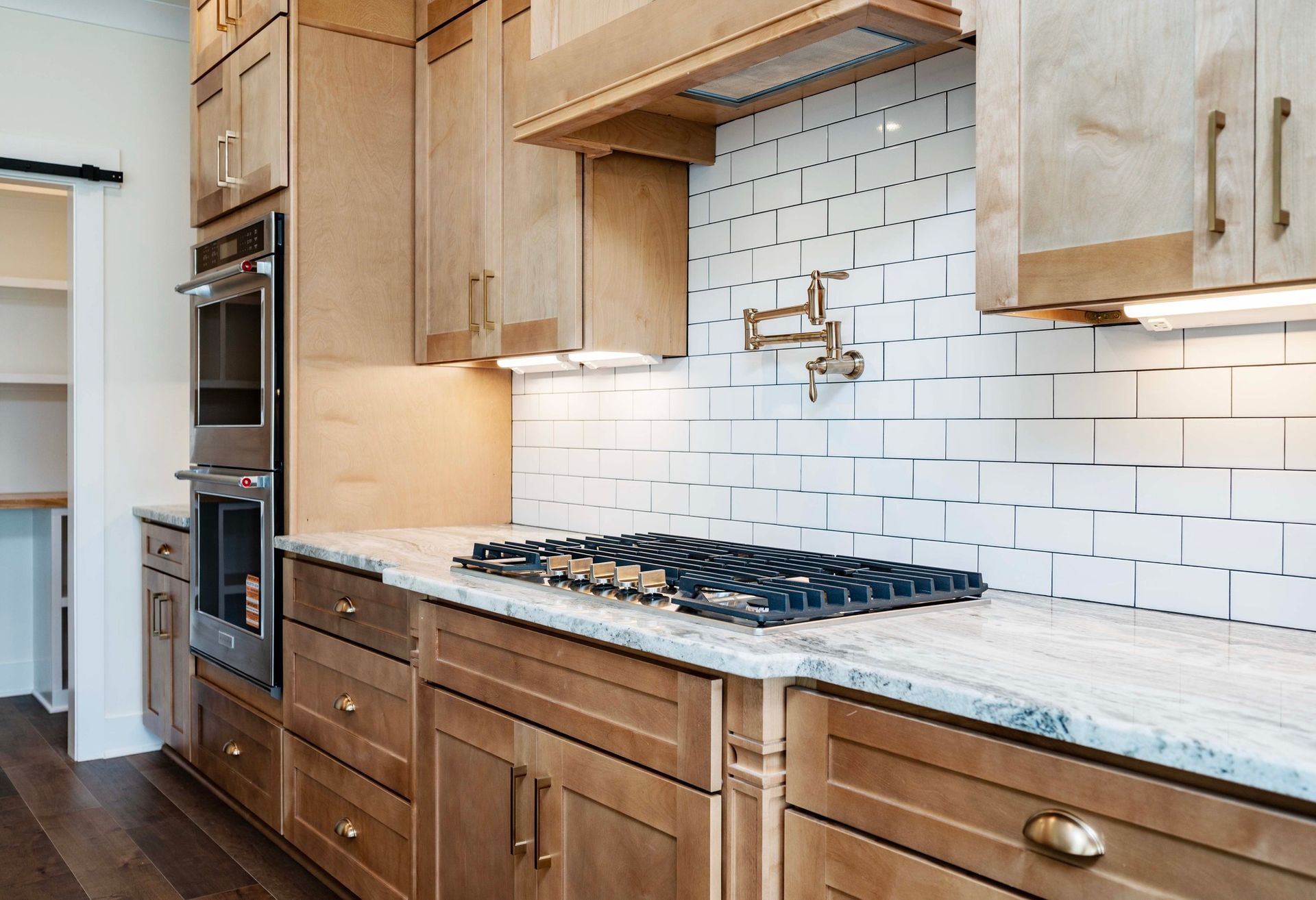 Kitchen with light wood cabinets, white subway tile backsplash, and a granite countertop.