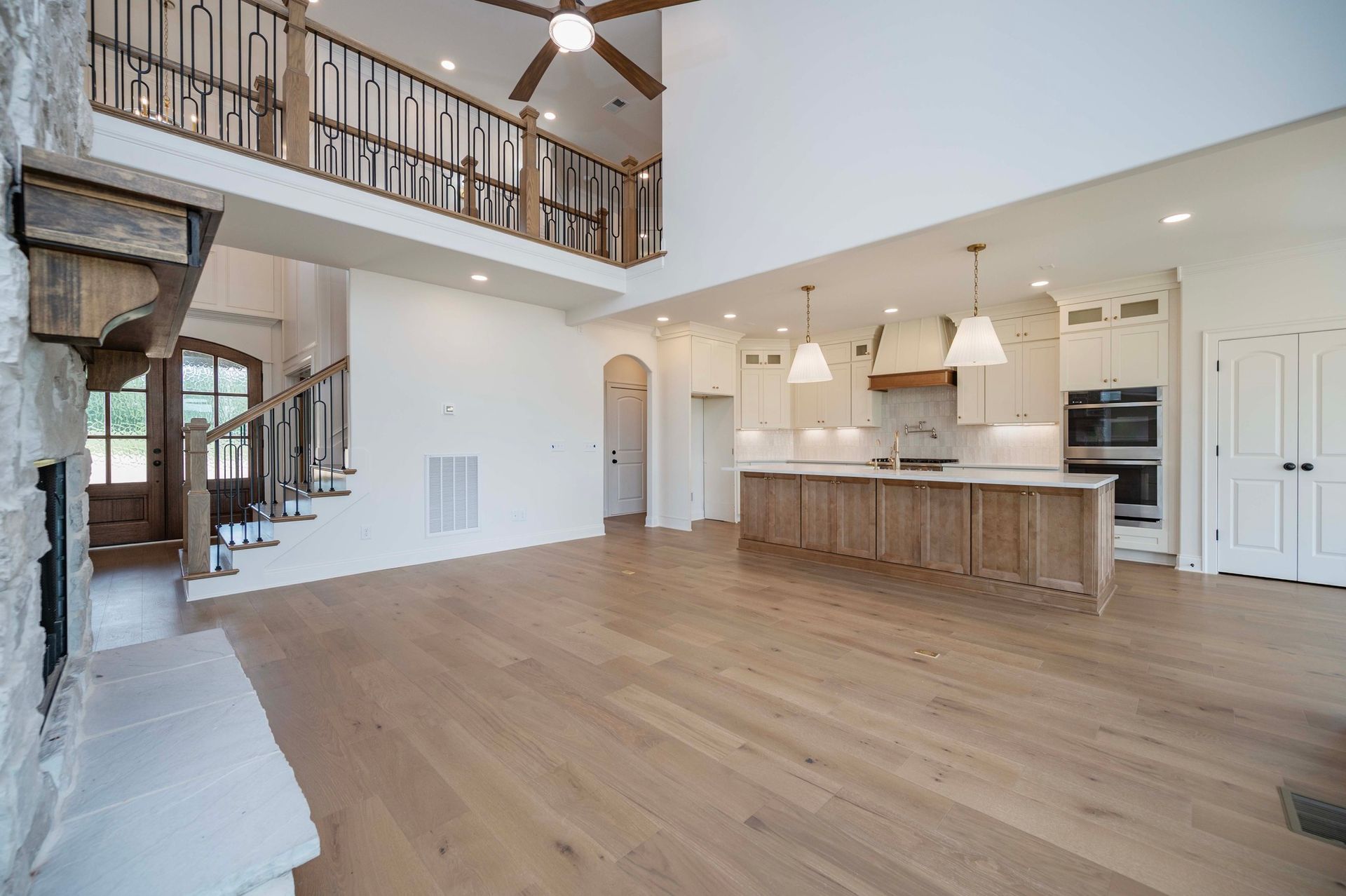 Spacious open-concept kitchen and living area with a two-story ceiling and hardwood floors.