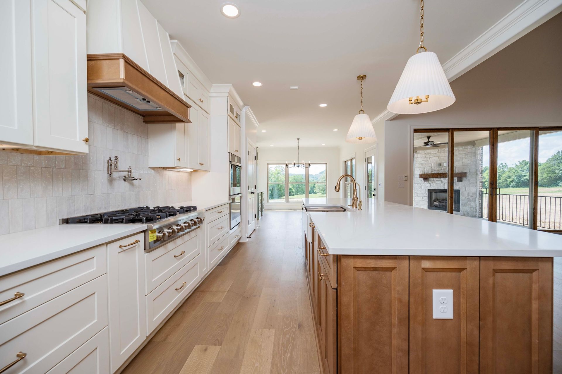 Bright kitchen with white and wood cabinets, a large island, and a view of an outdoor patio.