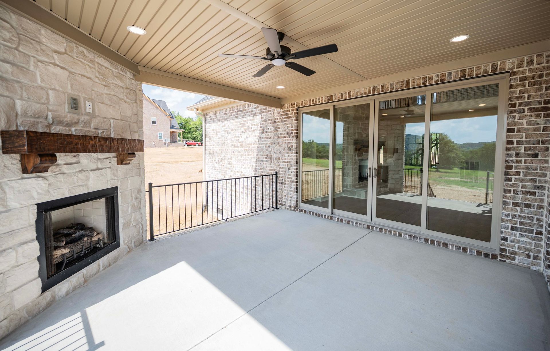 Covered patio with fireplace and sliding glass doors, brick and stone exterior.