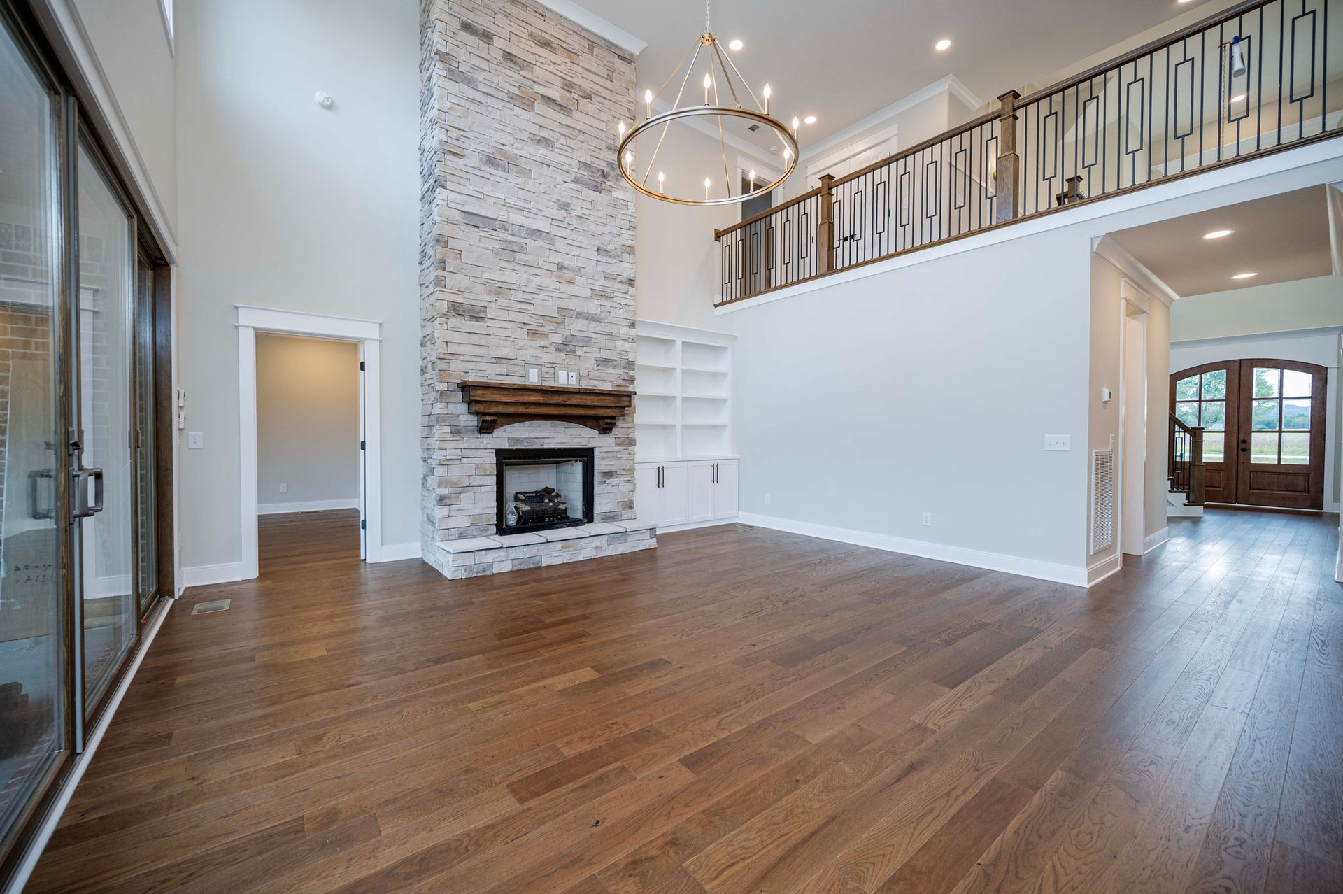Spacious living room with brick fireplace, hardwood floors, and balcony.