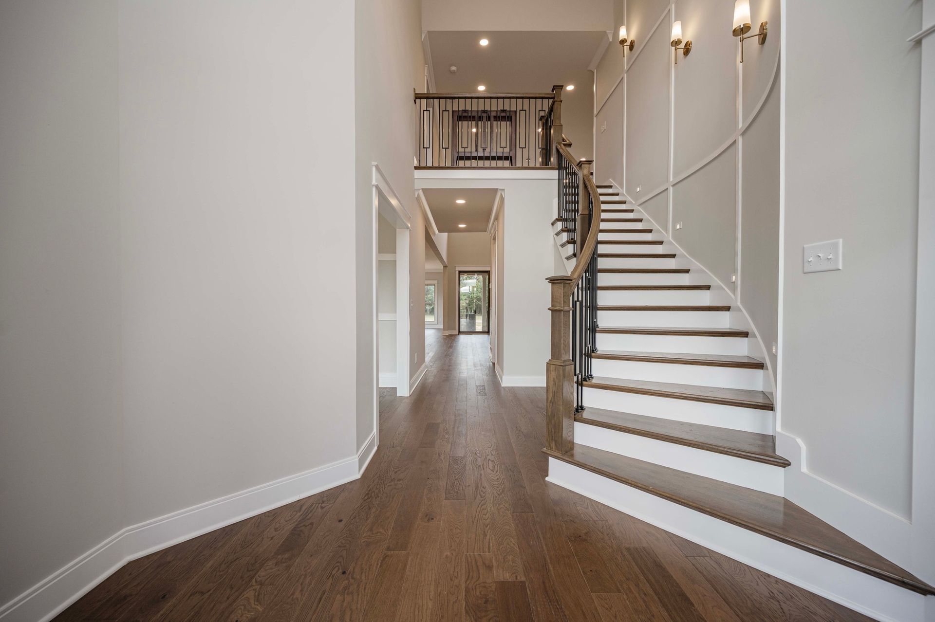 Interior view of a home entrance with hardwood floors, a staircase, and a second-floor landing.