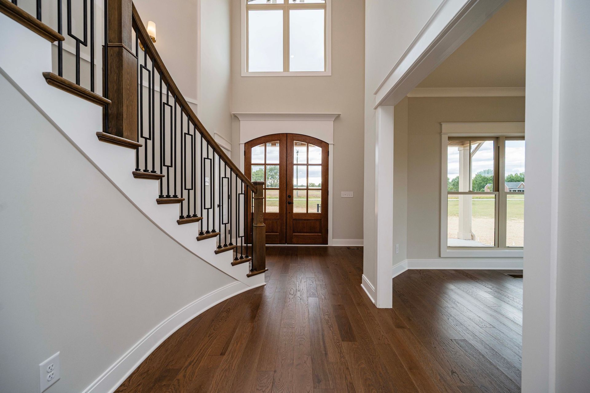 Entryway with staircase, dark wood floors, and double front doors.